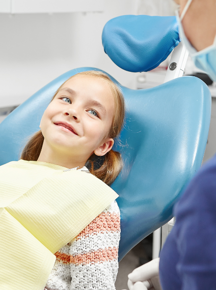 Niña pequeña feliz en la consulta de su dentista en Coraldent